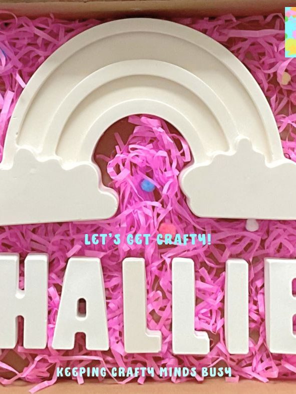 Rainbow kids gift. Pink tissue paper under large plaster of Paris rainbow, name spelling Hallie, six paints.