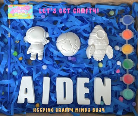 A astronaut, a rocket and earth in centre of picture sitting on blue shredded tissue paper. Name spelling Aidem